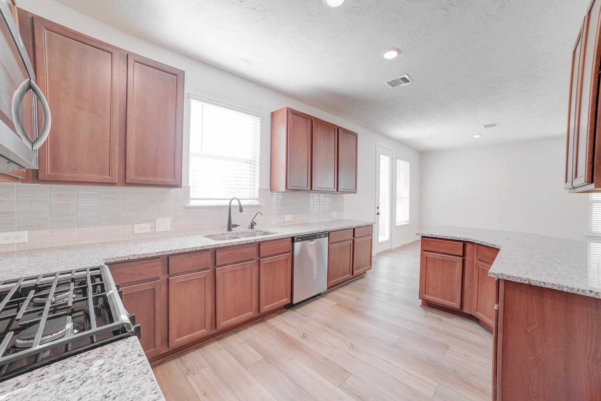 9307 Central Place Magnolia, TX 77354 - Photo 3 of 21 a kitchen with granite countertop wooden cabinets and a stove top oven