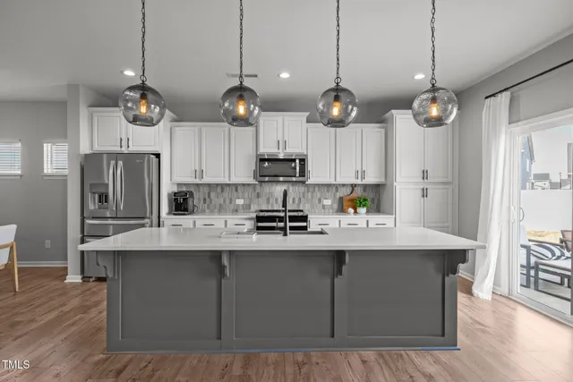 a kitchen with stainless steel appliances granite countertop a sink a stove a refrigerator and island with wooden floor