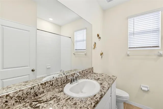 a bathroom with a granite countertop sink toilet and shower