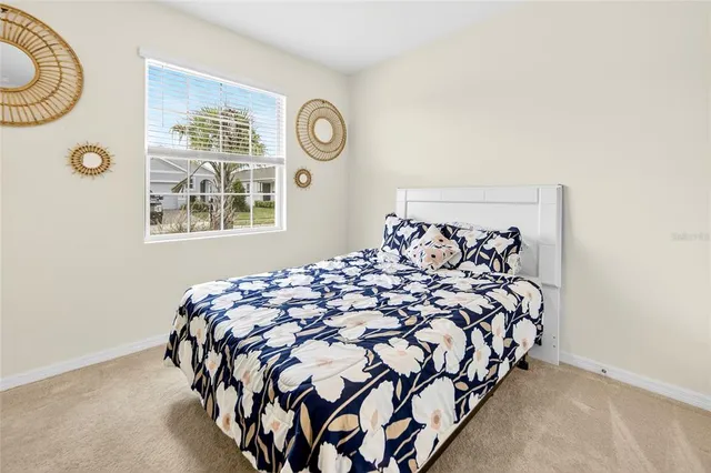 a bed sitting in a bedroom next to a window and a chair