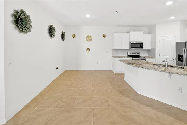 a large white kitchen with kitchen island a sink stainless steel appliances and cabinets