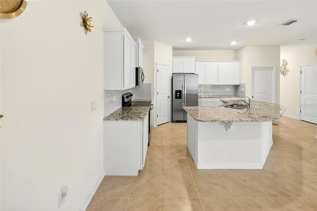 a kitchen with kitchen island a counter top space a sink stainless steel appliances and cabinets