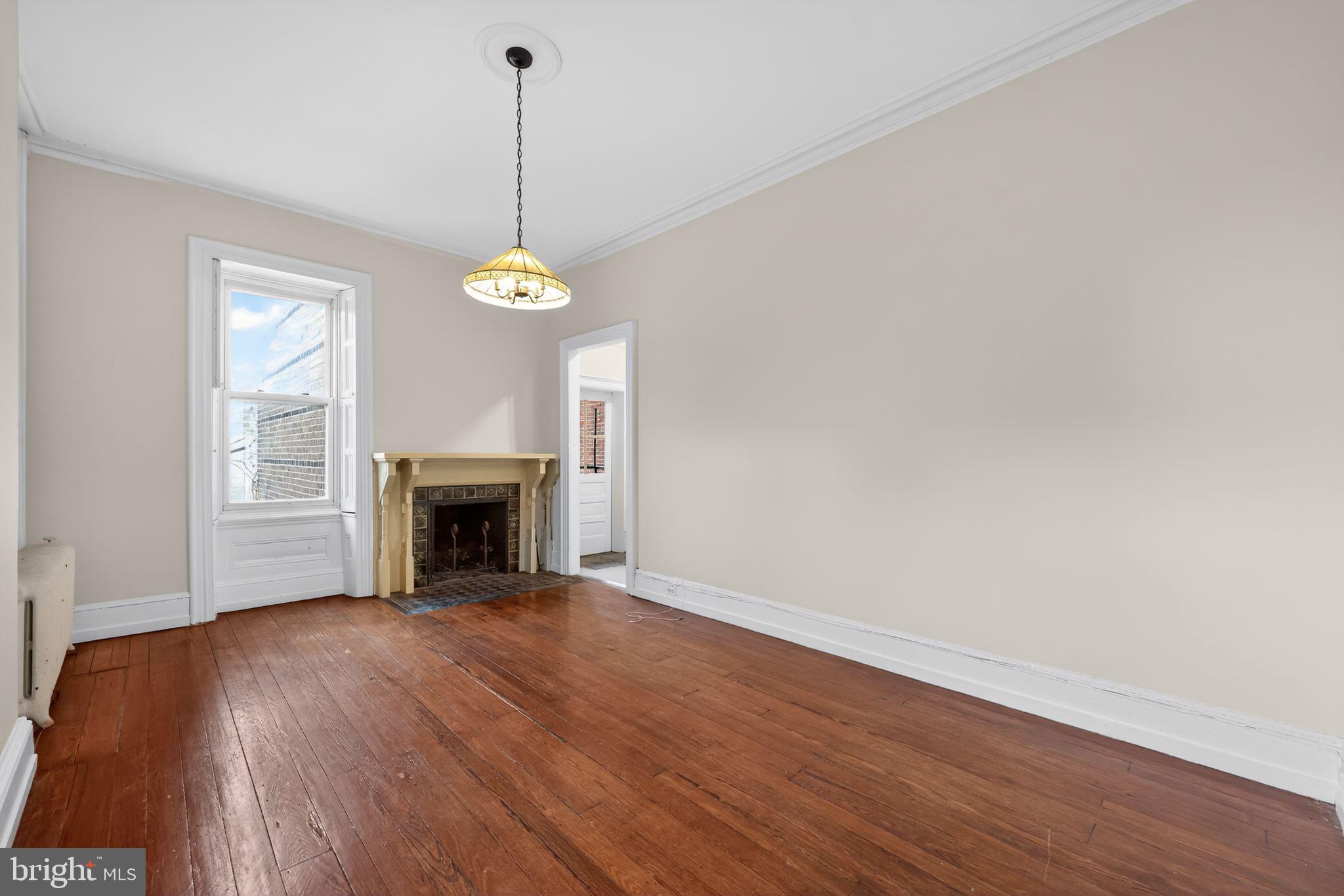 2117 Spruce Street, Unit 3 Philadelphia, PA 19103 - Photo 7 of 14 a view of a room with wooden floor a fireplace and a window