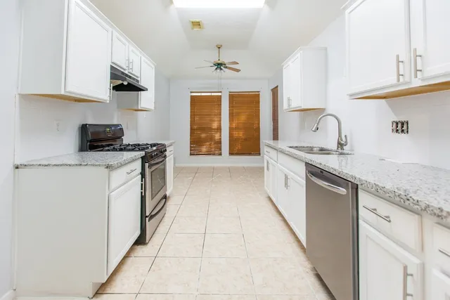 a kitchen with stainless steel appliances granite countertop a sink stove and cabinets