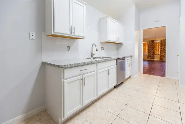 a kitchen with stainless steel appliances granite countertop a sink and dishwasher with white cabinets