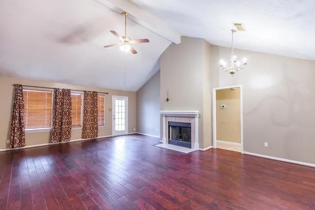 an empty room with wooden floor fireplace and windows