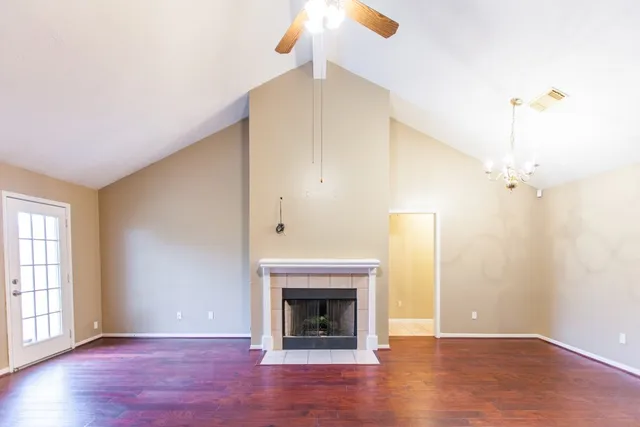an empty room with wooden floor fireplace and windows