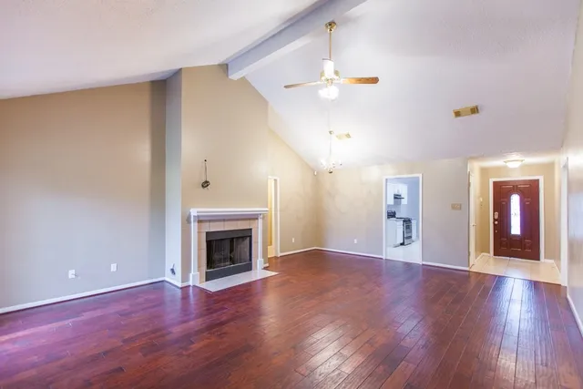 a view of an empty room with wooden floor fireplace and a window