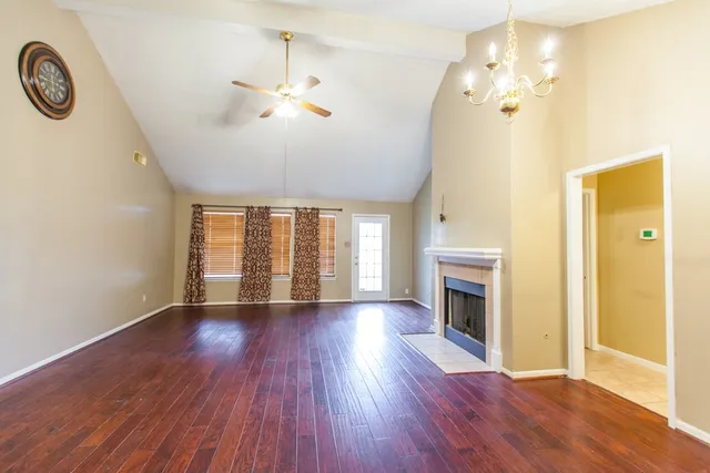 an empty room with wooden floor fireplace and windows