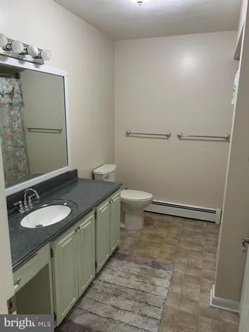 a bathroom with a granite countertop sink a toilet and a mirror