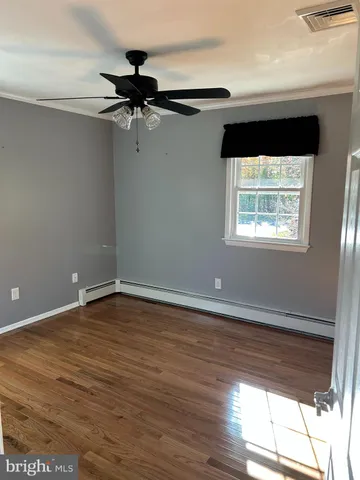 a view of empty room with wooden floor and fan