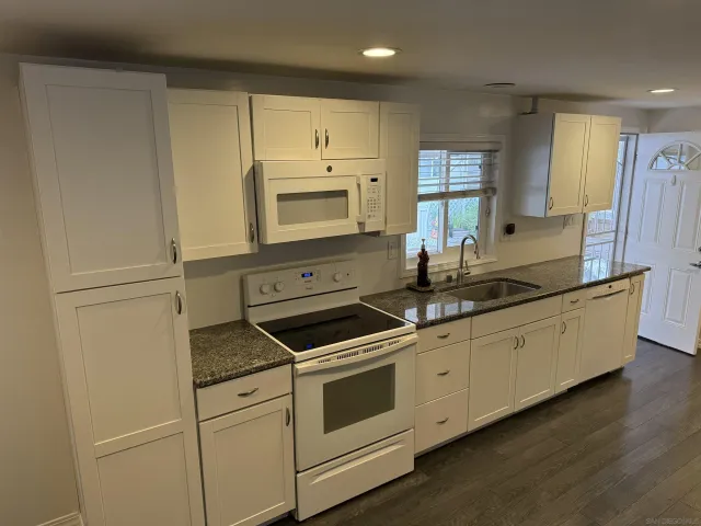 a kitchen with granite countertop white cabinets and white appliances