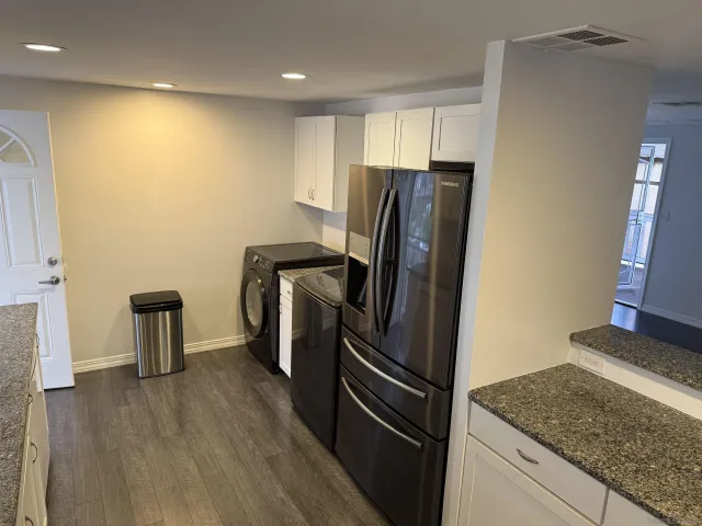 a view of a kitchen with refrigerator and wooden floor