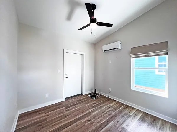 a view of empty room with wooden floor and fan