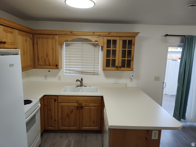 1735 West 540 North, Unit 1402 St. George, UT 84770 - Photo 5 of 14 Kitchen with a peninsula, brown cabinetry, light countertops, glass insert cabinets, and white appliances