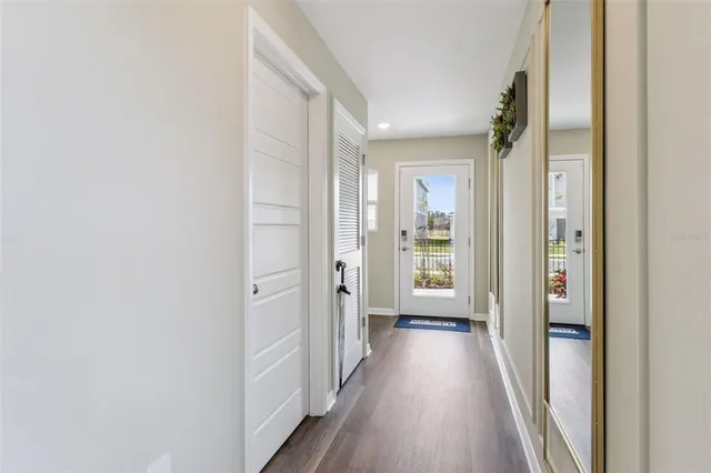 a view of a hallway with wooden floor and a bathroom