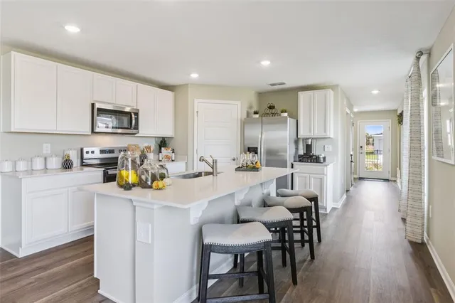 a kitchen with a sink a stove a refrigerator and white cabinets with wooden floor