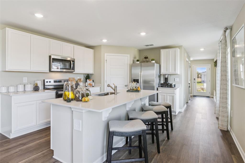 3433 Nettle Loop Tavares, FL 32778 - Photo 5 of 31 a kitchen with a sink a stove a refrigerator and white cabinets with wooden floor