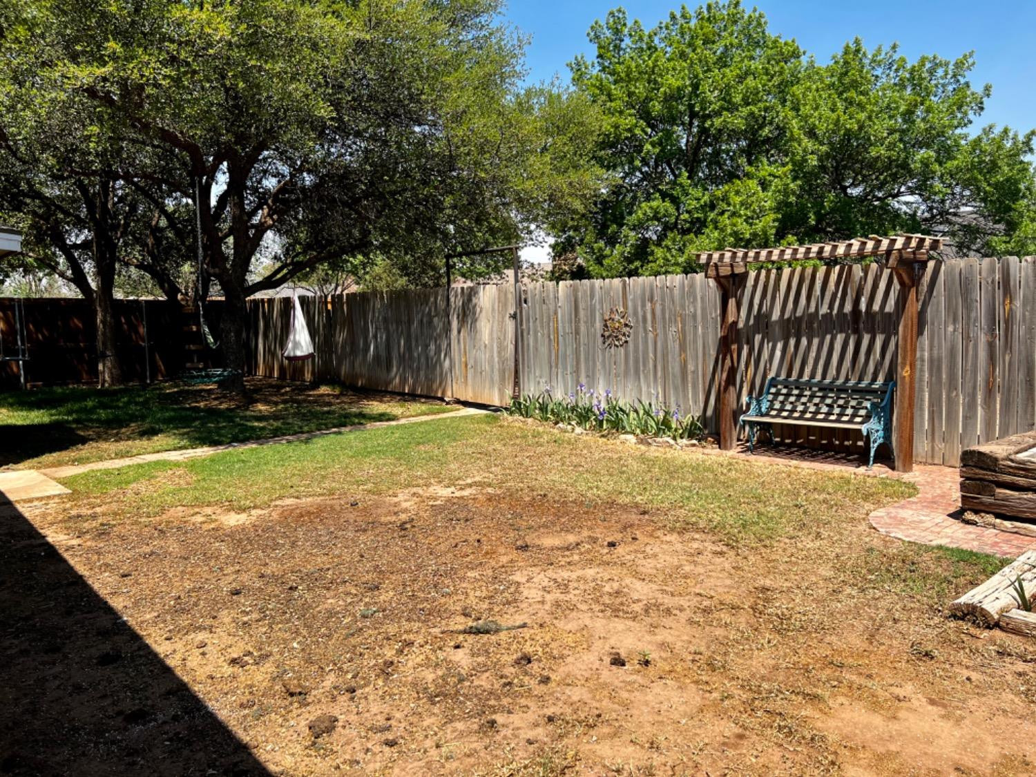 5724 92nd Street Lubbock, TX 79424 - Photo 14 of 18 a view of a backyard with wooden fence and large trees