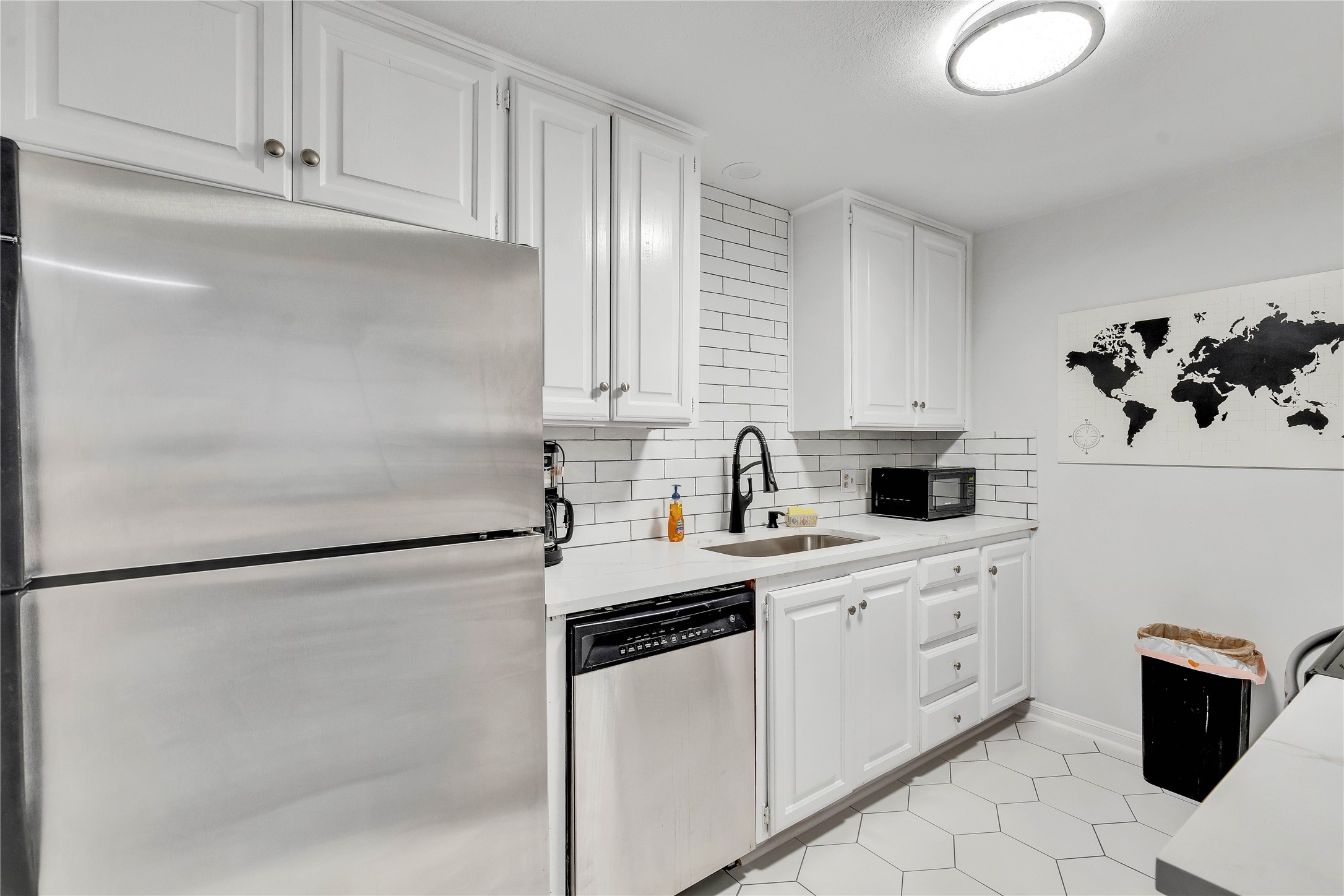 2529 Rio Grande Street, Unit 56 Austin, TX 78705 - Photo 2 of 16 Kitchen with a sink, white cabinets, light countertops, appliances with stainless steel finishes, and tasteful backsplash