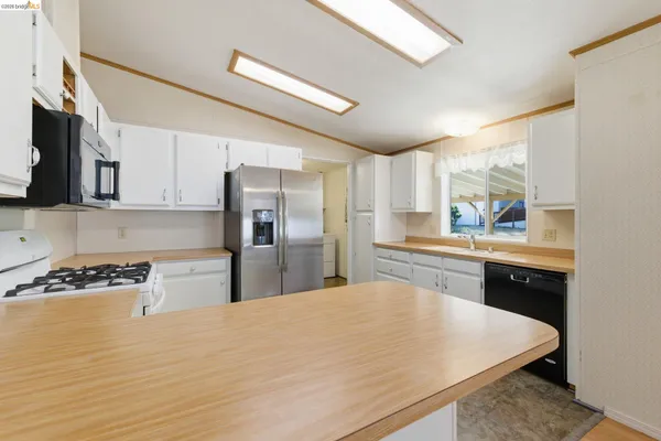 a kitchen with stainless steel appliances granite countertop a sink a stove and refrigerator