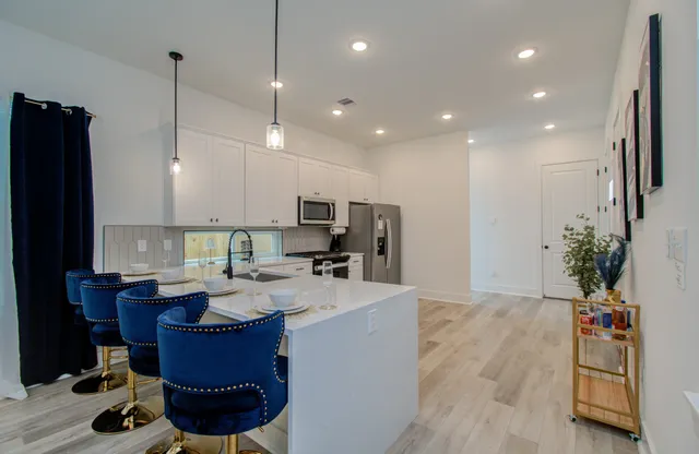 a large kitchen with sink a refrigerator and chairs