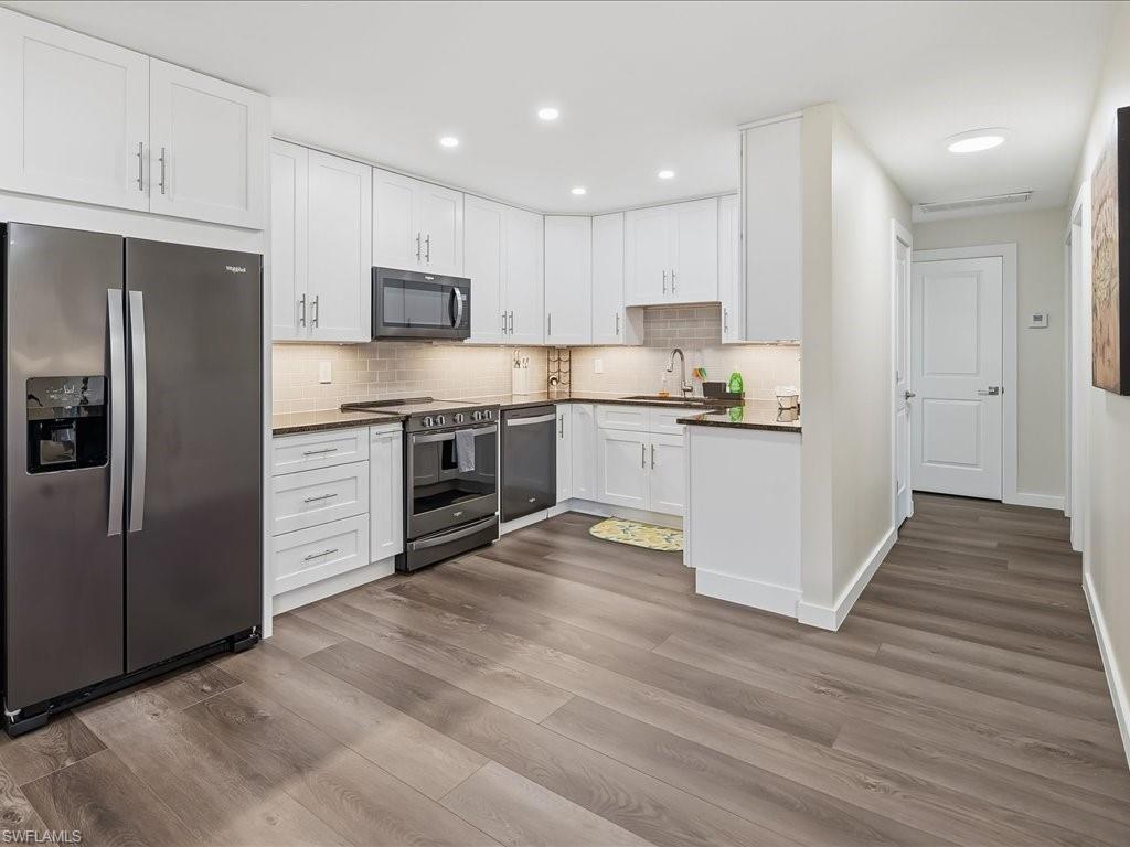 186 Harrison Road, Unit H2 Naples, FL 34112 - Photo 19 of 38 a kitchen with stainless steel appliances granite countertop a refrigerator a stove top oven a sink and dishwasher with wooden floor