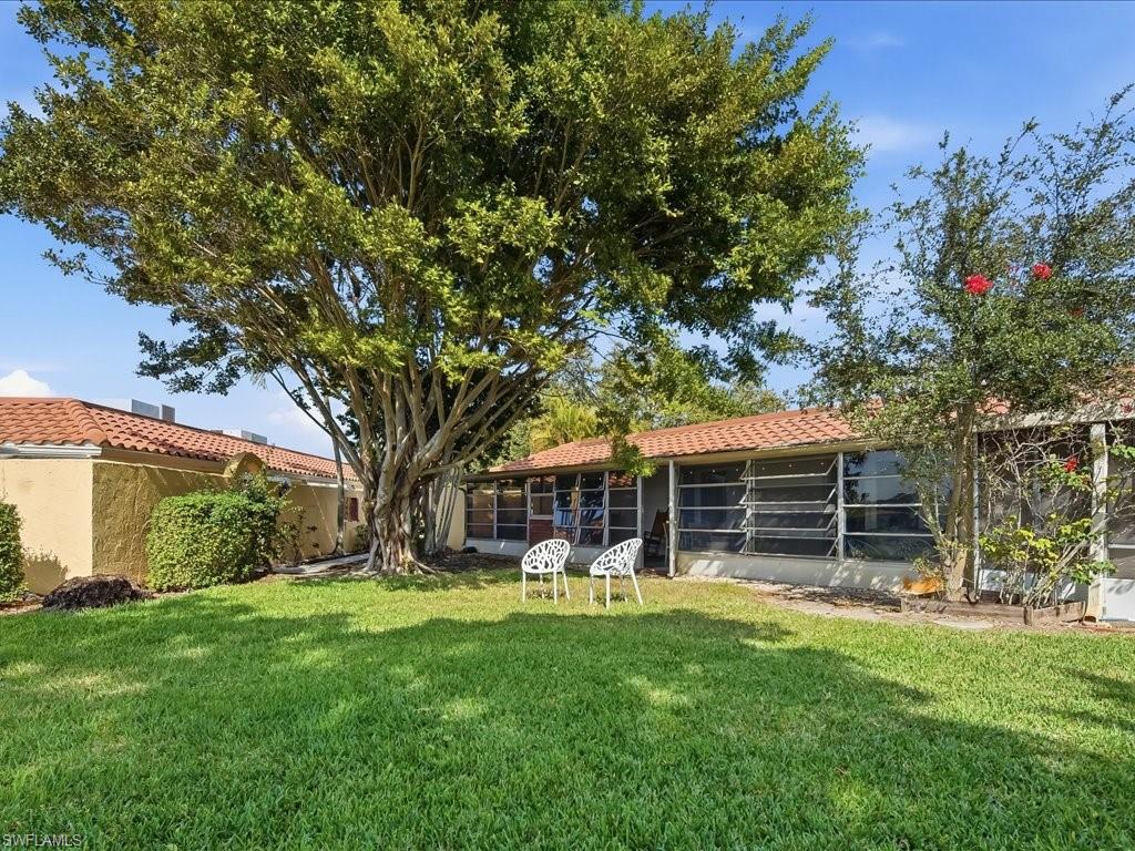 186 Harrison Road, Unit H2 Naples, FL 34112 - Photo 34 of 38 a view of a house with a backyard and a large tree