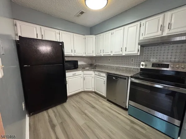 a kitchen with a sink dishwasher a refrigerator and cabinets
