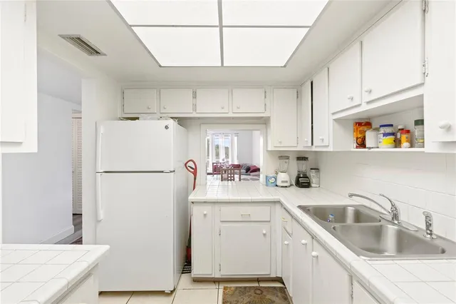 a kitchen with a sink a refrigerator and cabinets