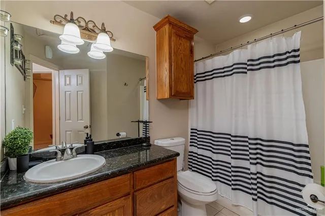 a bathroom with a sink a toilet a mirror and shower curtain
