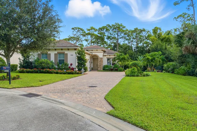 a front view of a house with a yard and potted plants