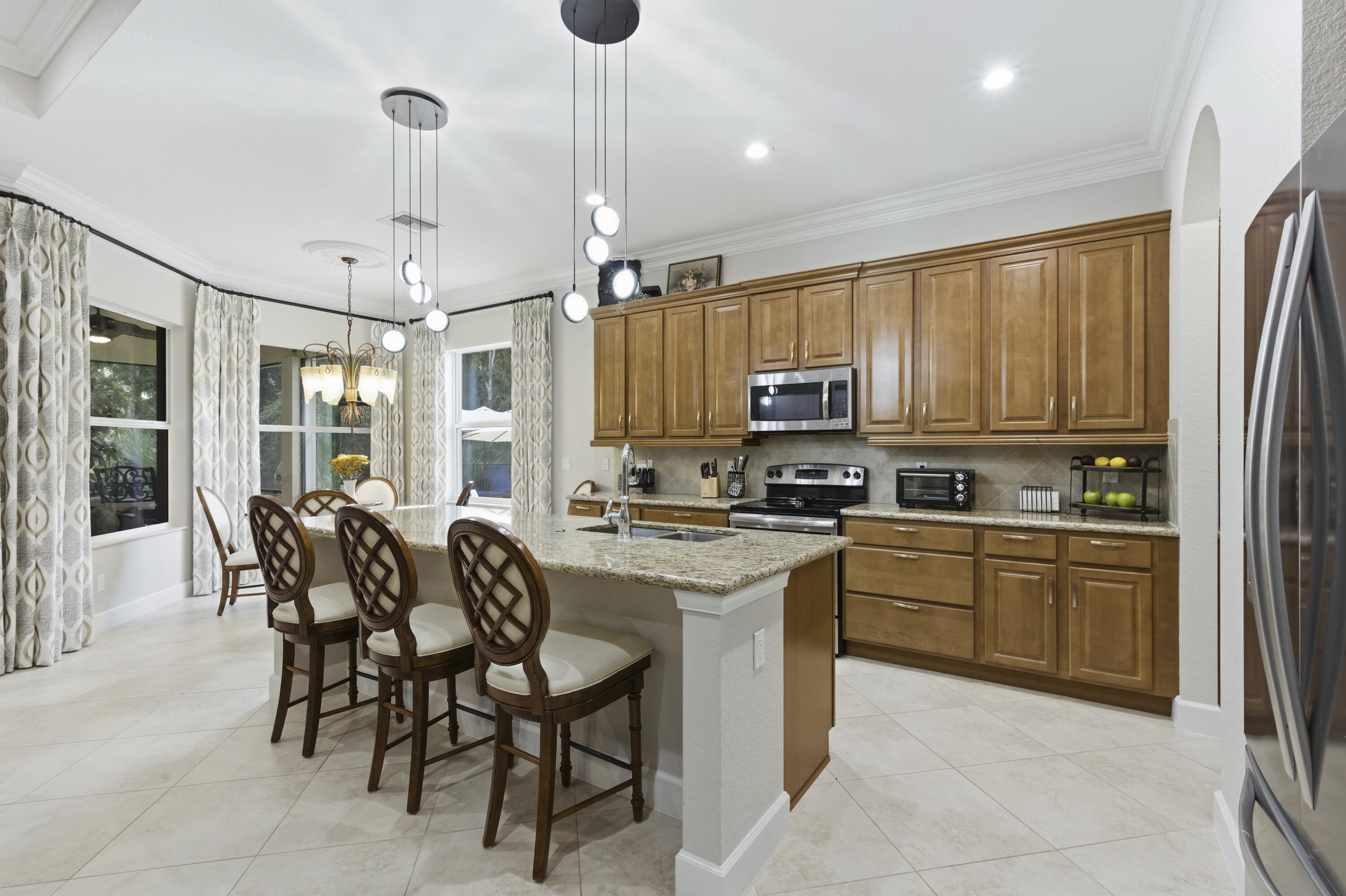 1016 Southwest Triste Way Stuart, FL 34997 - Photo 8 of 41 a kitchen with stainless steel appliances granite countertop a stove top oven a sink dishwasher a dining table and chairs with wooden floor