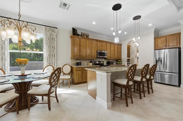 a kitchen with stainless steel appliances kitchen island granite countertop a table chairs and a refrigerator