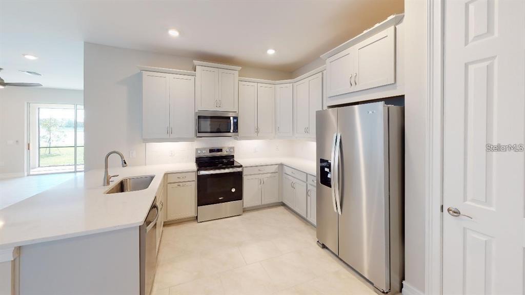 127 Ibiza Loop Venice, FL 34292 - Photo 3 of 20 a kitchen with a refrigerator a sink a stove a microwave a counter top space and cabinets