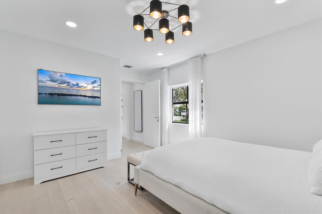 9 Tahoe Lane Sea Ranch Lakes, FL 33308 - Photo 33 of 99 a bedroom with a large bed and a chandelier