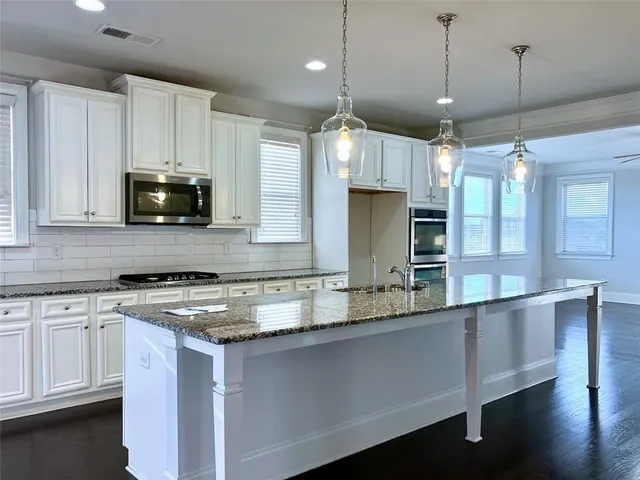 a kitchen with stainless steel appliances granite countertop a refrigerator a stove and a wooden floors