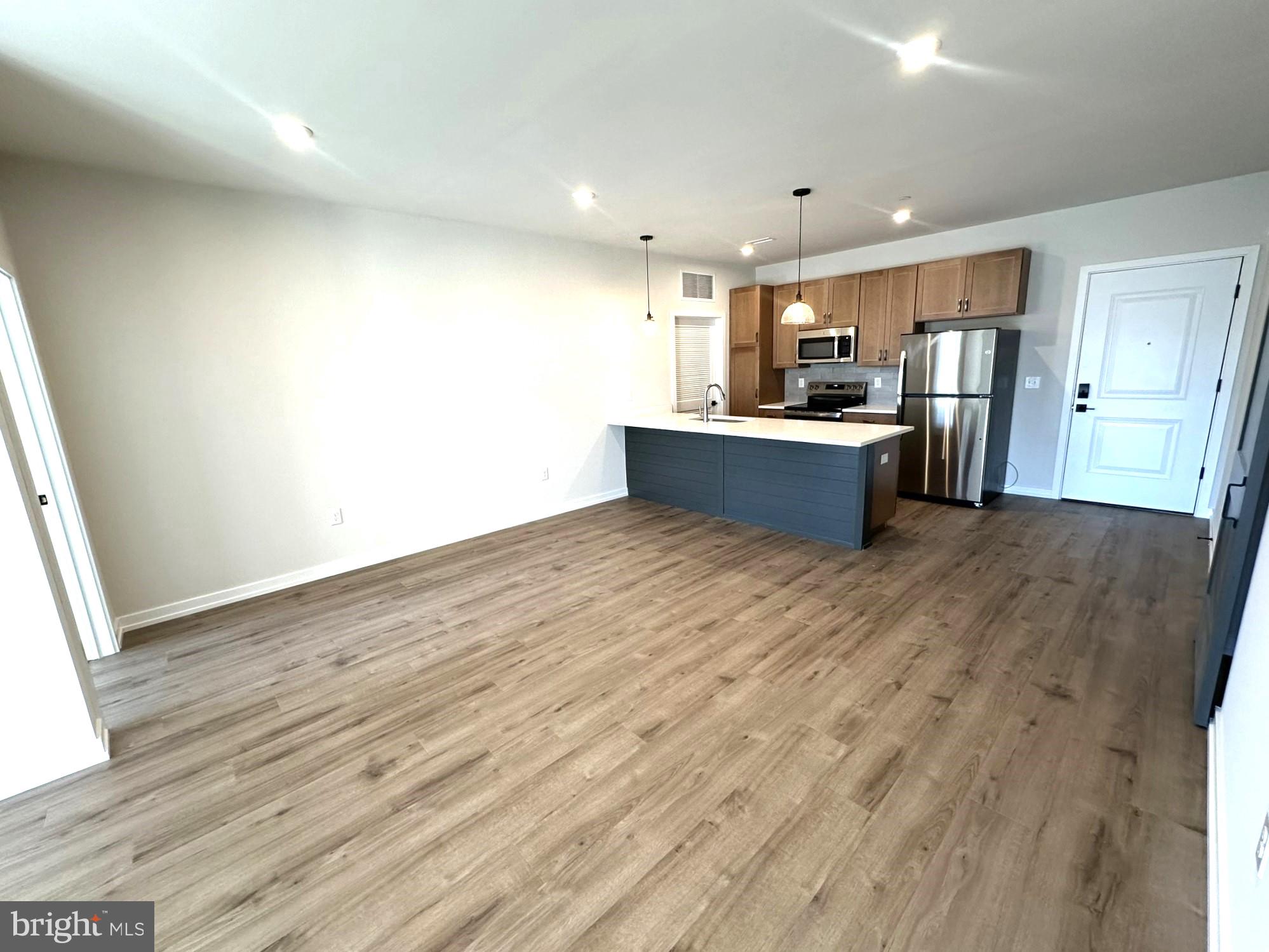 409 West Butler Avenue, Unit 223 Chalfont, PA 18914 - Photo 13 of 33 a large kitchen with stainless steel appliances kitchen island a large counter top and a wooden floor