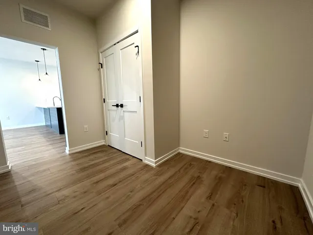 a view of an empty room with wooden floor and a bathroom