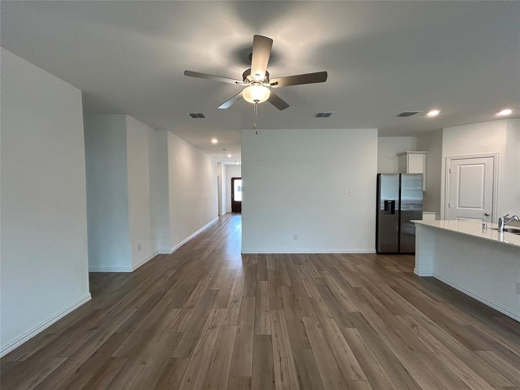 213 Post Oak Street Azle, TX 76020 - Photo 11 of 24 a view of an empty room with wooden floor and a kitchen