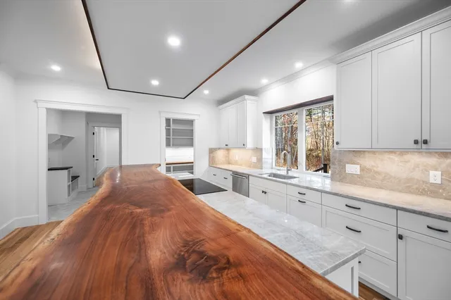 a large white kitchen with a sink and dishwasher a stove with wooden floor