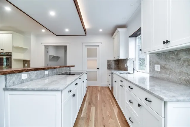 a view of a kitchen with kitchen island white cabinets and stainless steel appliances
