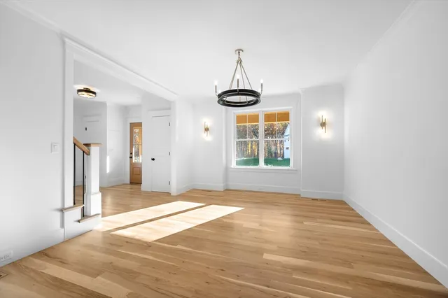 a view of an empty room with window and wooden floor