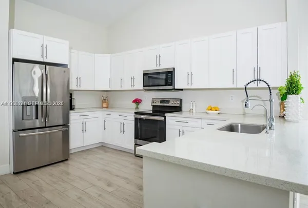 a kitchen with a refrigerator sink and white cabinets