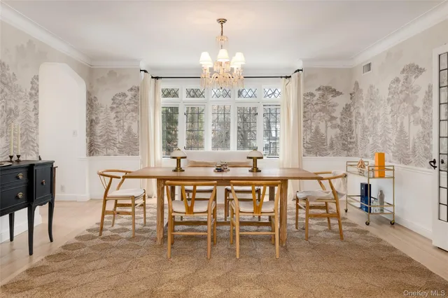 a dining room with wooden floor a chandelier a wooden table and chairs