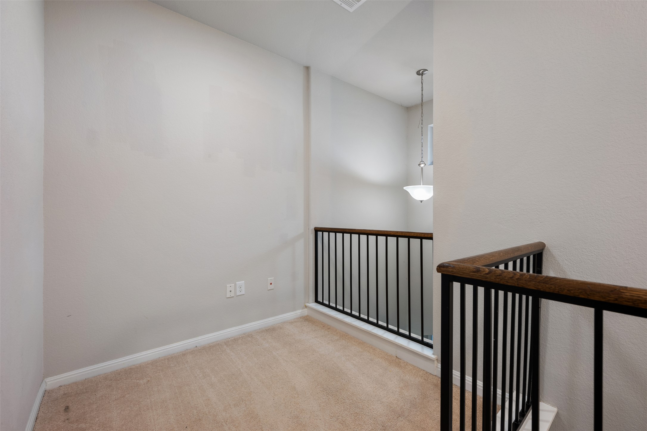 211 Parable Cove Pflugerville, TX 78660 - Photo 29 of 40 Carpeted loft area featuring a dark wood railing with black metal balusters, white baseboards, and neutral wall paint