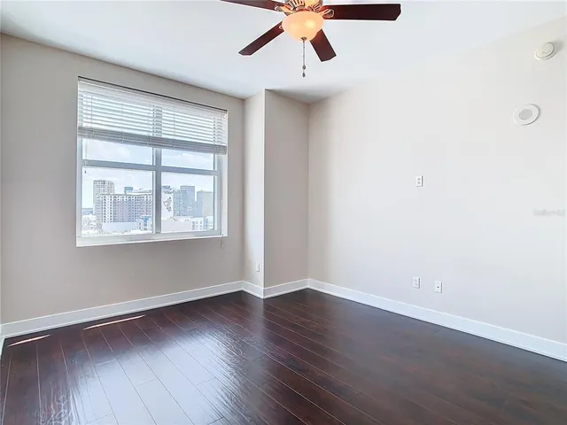 an empty room with wooden floor cabinet and windows