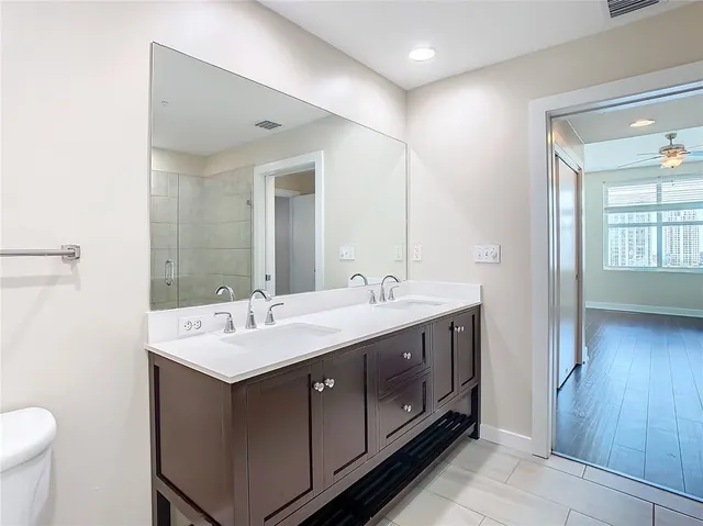 an empty room with wooden floor chandelier fan and windows