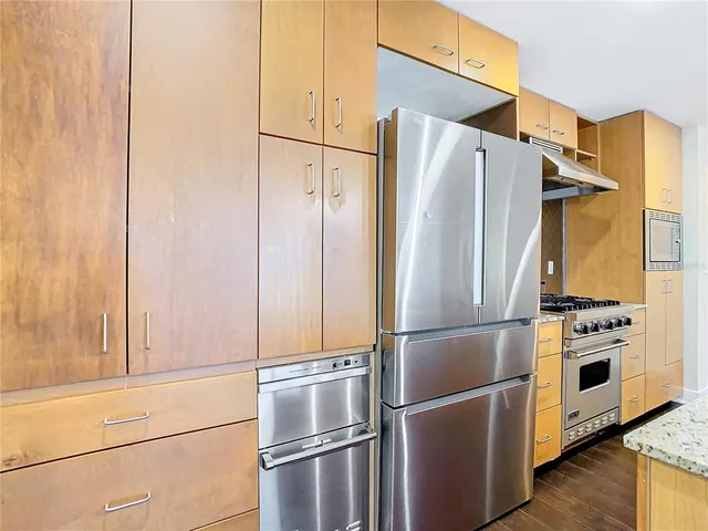 a kitchen with stainless steel appliances granite countertop a sink cabinets and wooden floor