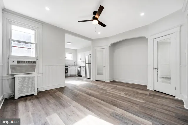 a view of an empty room with window and wooden floor